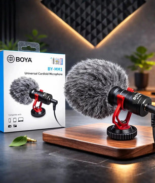 Boya BY-MM1 microphone on a wooden stand with its packaging in the background.
